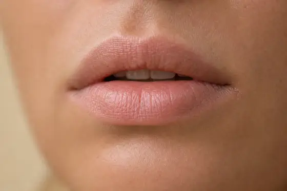 Lèvres nues légèrement gercées, texture naturelle, sans maquillage, lumière douce