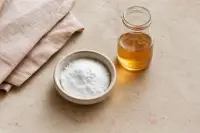 Bicarbonate de soude en poudre et vinaigre de cidre dans deux bols posés côte à côte sur un plan clair