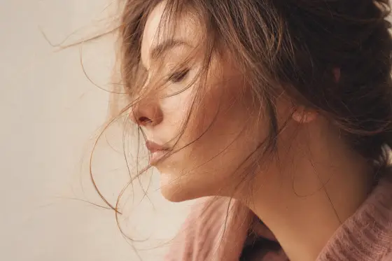 Mèches de cheveux légèrement soulevées captant la lumière, texture naturelle, fond neutre