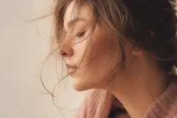 Mèches de cheveux légèrement soulevées captant la lumière, texture naturelle, fond neutre