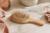 Brosse posée sur une surface claire avec quelques cheveux, lumière naturelle douce