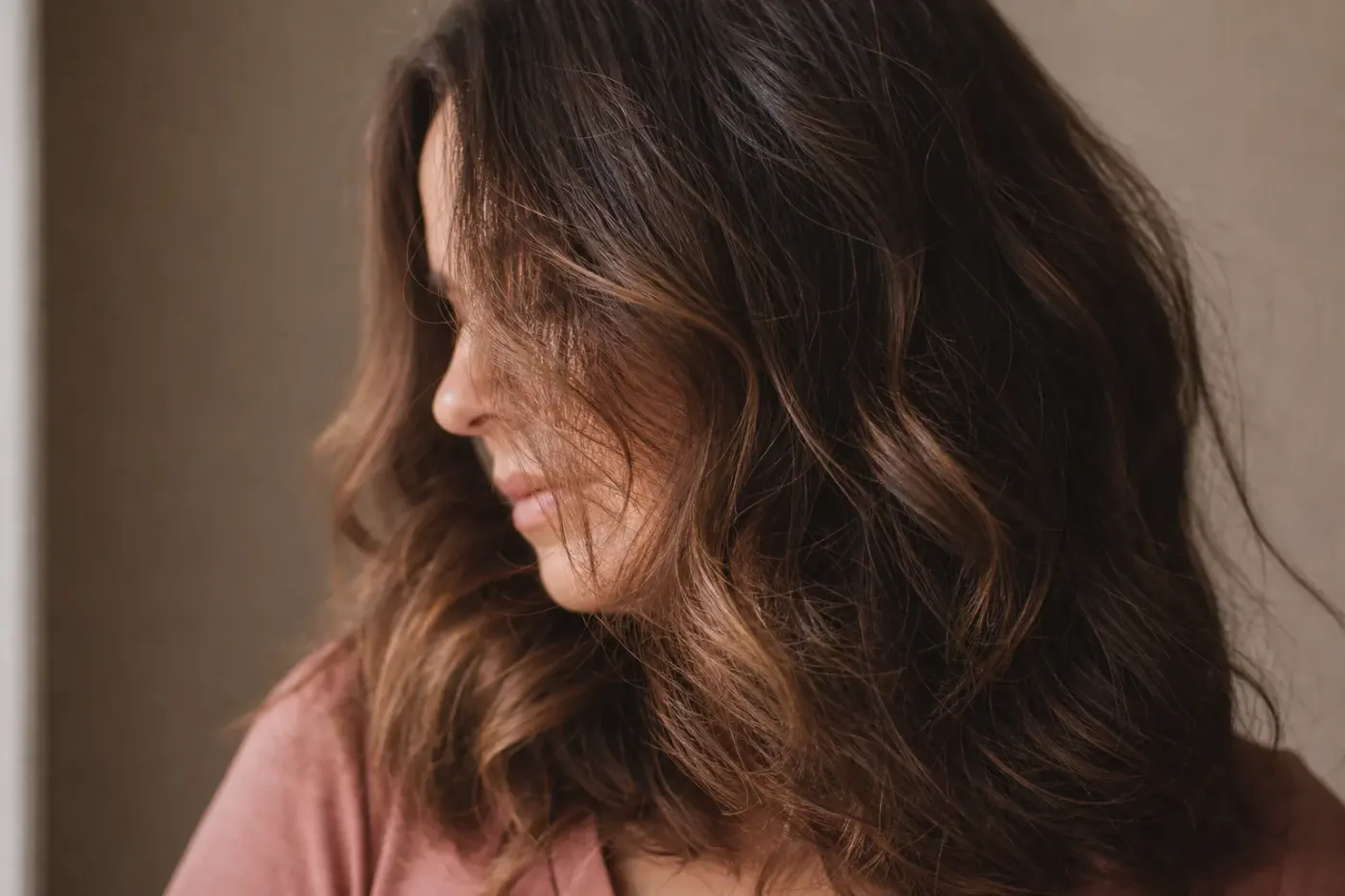 Chevelure ondulée et texturée d’une femme adulte, mèches naturelles visibles, lumière du jour douce
