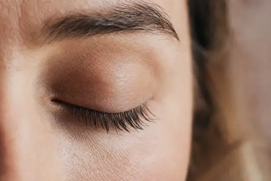 Œil fermé avec des cils longs et fournis, lumière naturelle douce