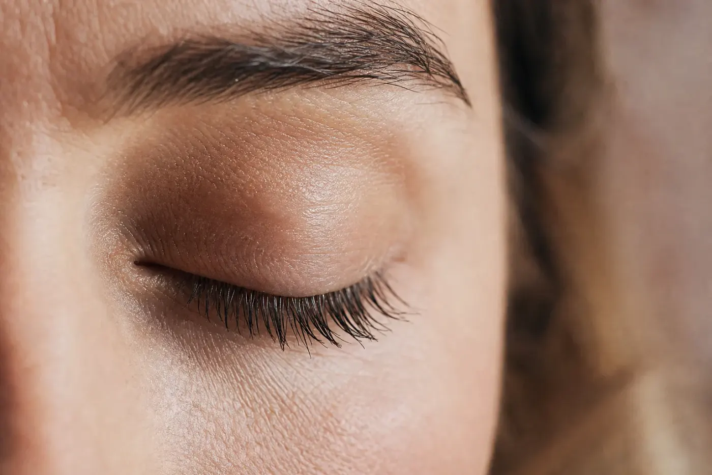 Œil fermé avec des cils longs et fournis, lumière naturelle douce