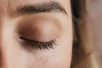 Œil fermé avec des cils longs et fournis, lumière naturelle douce