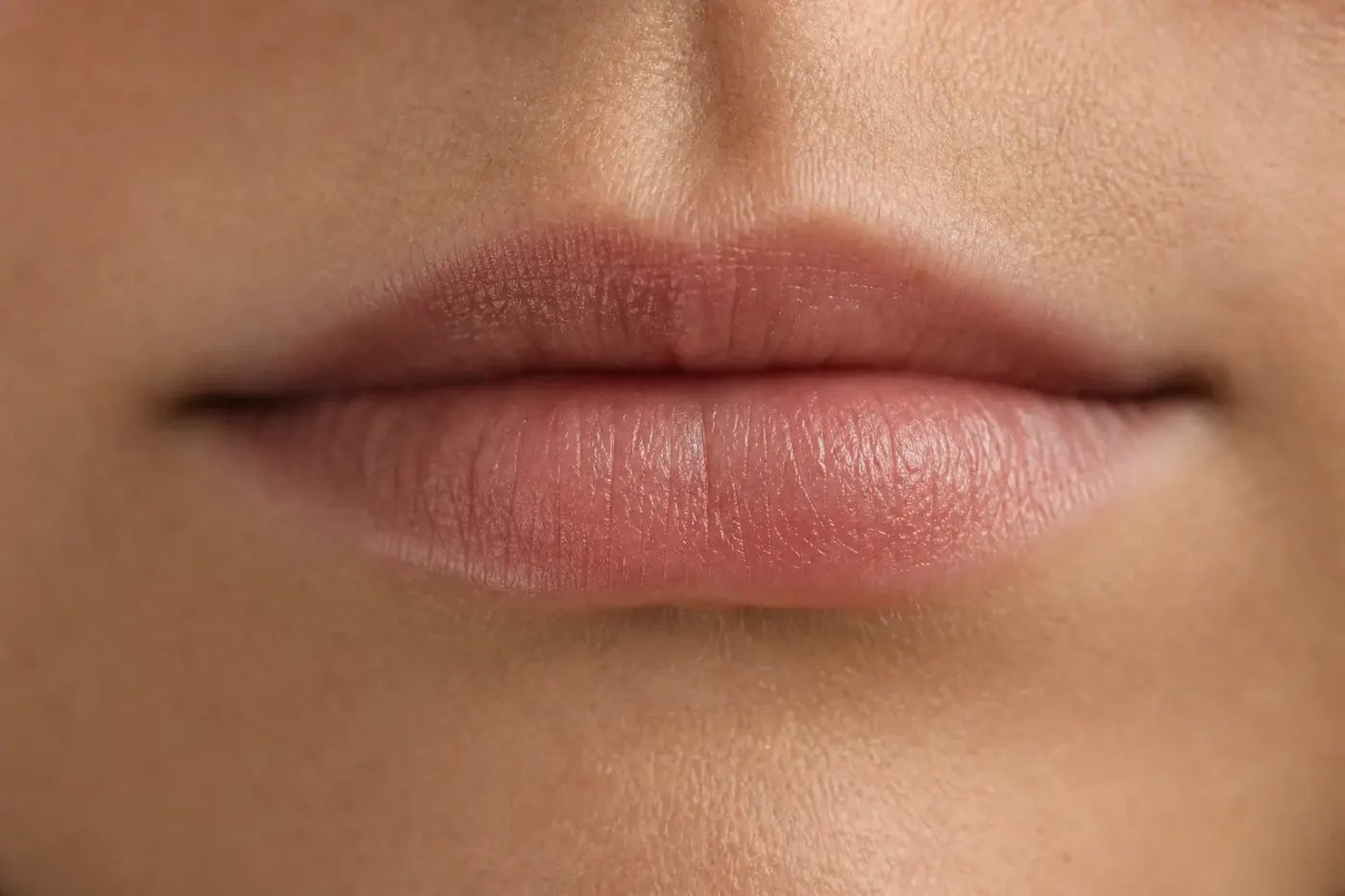 Gros plan sur des lèvres nues au naturel, éclairées par une lumière douce, sans maquillage
