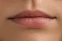 Gros plan sur des lèvres nues au naturel, éclairées par une lumière douce, sans maquillage