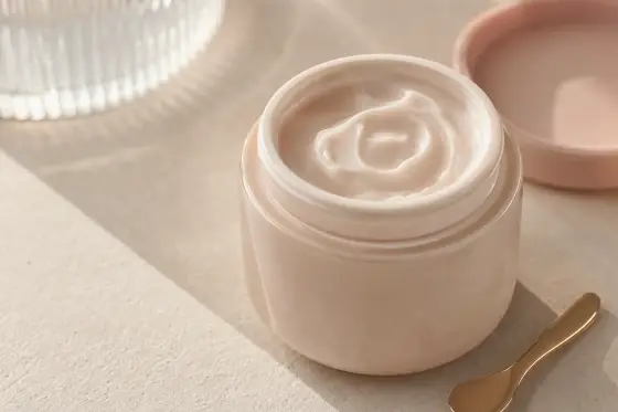 Pot de crème ouvert avec texture visible sur une surface claire, lumière naturelle douce