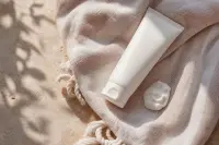 Tube de crème solaire posé sur une serviette claire, lumière naturelle d'été