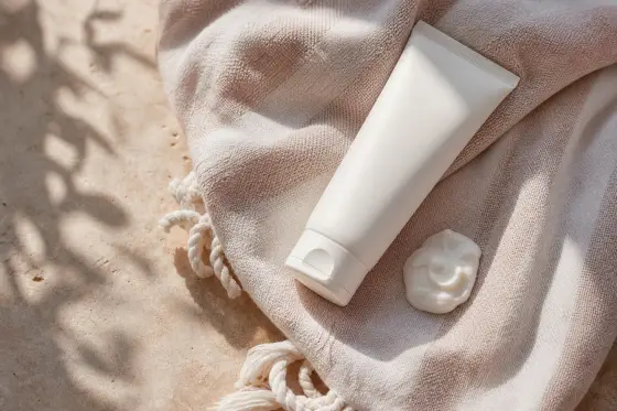 Tube de crème solaire posé sur une serviette claire, lumière naturelle d'été