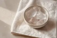 Glaçons dans un bol en céramique posé sur une serviette blanche, lumière naturelle