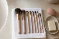 Pinceaux de maquillage propres séchant à plat sur une serviette près d’une éponge rosée