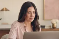 Femme adulte de face devant un ordinateur portable, lumière douce de face, maquillage discret et net