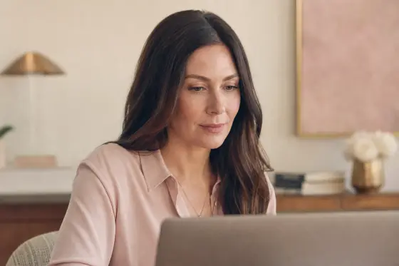 Femme adulte de face devant un ordinateur portable, lumière douce de face, maquillage discret et net