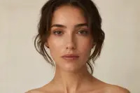 Visage de face avec un maquillage léger et naturel, expression neutre, fond clair uni