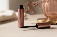 Tube de mascara ouvert avec sa brosse posée à côté, lumière naturelle douce