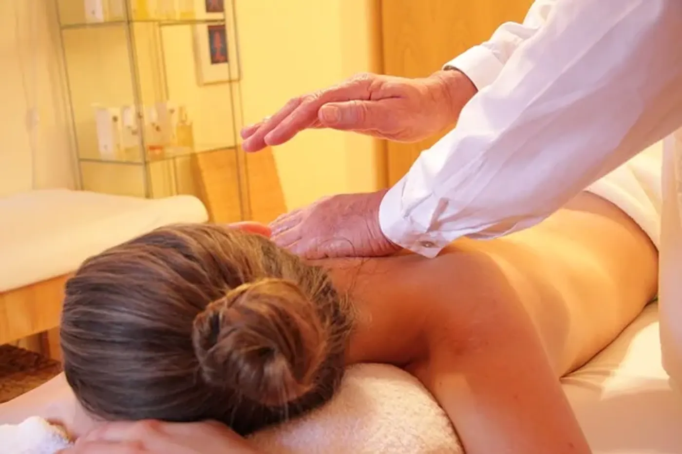 Cabine de massage lumineuse avec table recouverte d’un drap blanc, huile et serviettes pliées