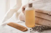 Peigne fin en bois, flacon de shampoing doux sans étiquette et serviette sur un plan clair