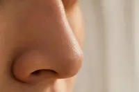 Gros plan sur l'arête d'un nez avec une peau texturée éclairée par une lumière douce et naturelle