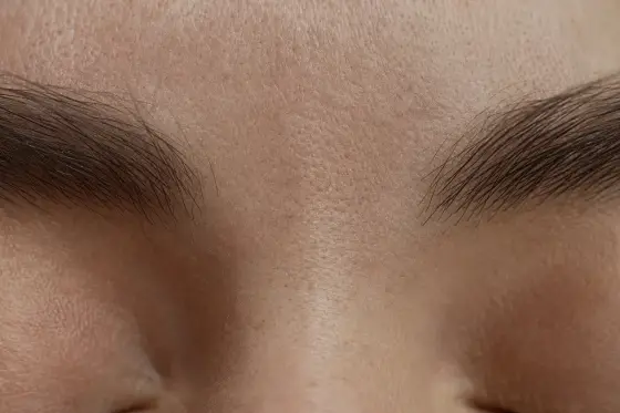 Gros plan sur le front et l'espace entre les sourcils d'un visage adulte détendu, lumière douce