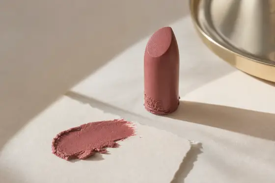 Rouge à lèvres sorti de son étui posé à côté de la trace de couleur laissée sur du papier