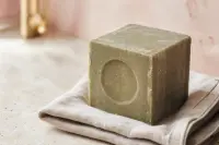 Cube de savon de Marseille traditionnel posé sur une surface claire, texture naturelle
