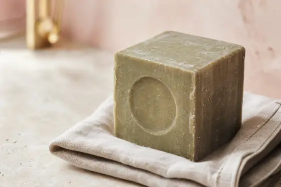 Cube de savon de Marseille traditionnel posé sur une surface claire, texture naturelle