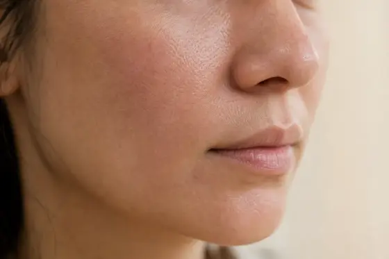 Joue et pourtour de la bouche d’une femme adulte en gros plan, sans maquillage, en lumière naturelle douce
