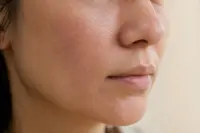 Joue et pourtour de la bouche d’une femme adulte en gros plan, sans maquillage, en lumière naturelle douce