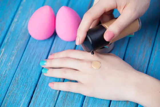 Trois traînées de fond de teint appliquées sur une mâchoire, près d’une fenêtre