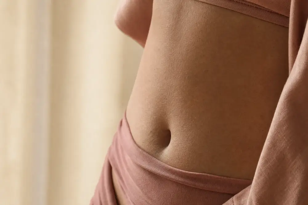 Peau du ventre en gros plan, texture naturelle sans marque visible, lumière douce