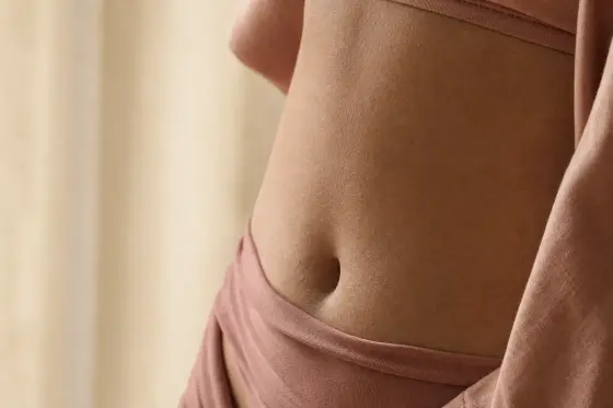 Peau du ventre en gros plan, texture naturelle sans marque visible, lumière douce